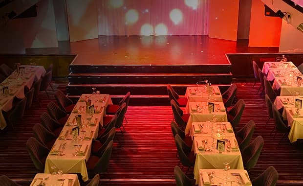 Seated dining setup with front row tables offering close-up views of a live cabaret on Showboat cruise